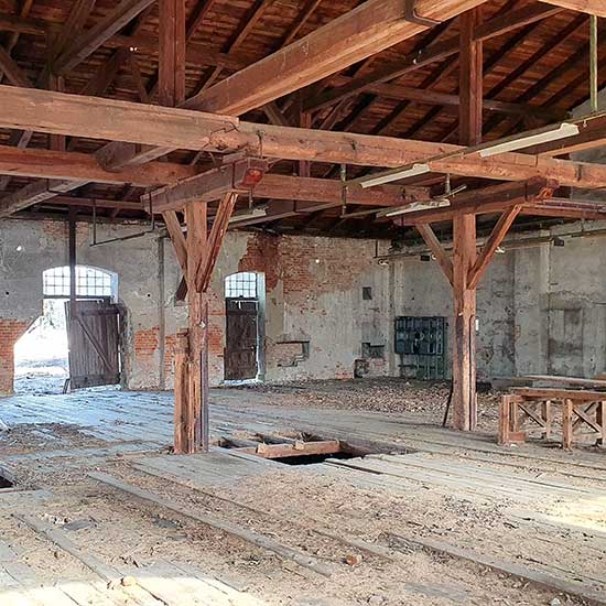 Innenansicht einer Industriebrache mit vielfältigen Baustoffen, u.a. Holzboden und -tragwerk und Ziegelmauerwerk