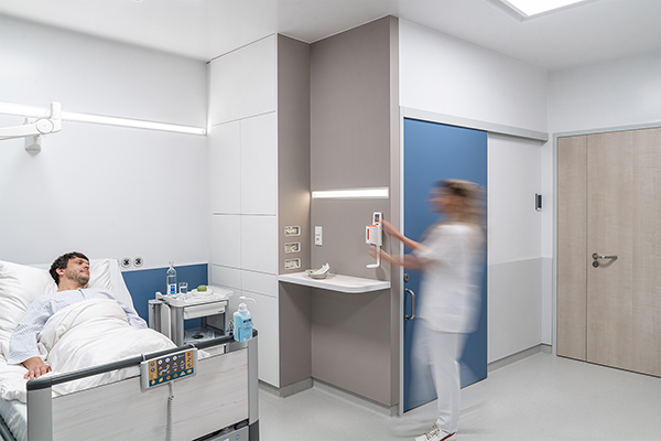 Krankenzimmer mit optimierter Integration von Arbeitsplatte und Desinfektionsmittelspender in die Arbeitsprozesse
