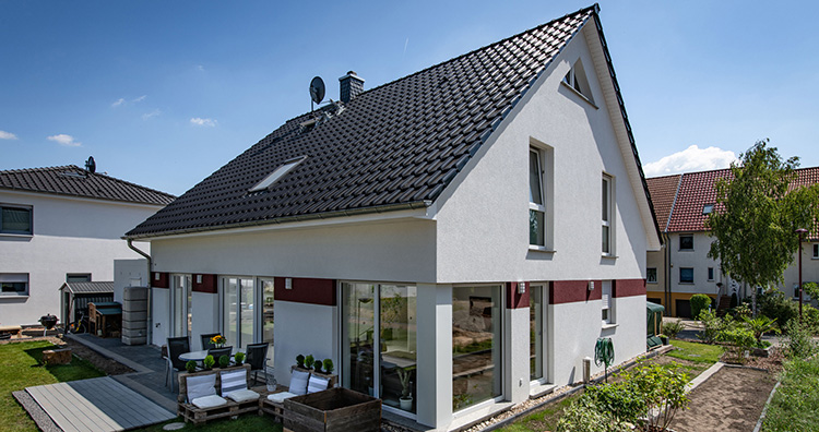 Massives Einfamilienhaus, errichtet von Helma Eigenheimbau in Blankenfelde-Mahlow (Land Brandenburg). Die monolithische, aus porosierten Hochlochziegeln aufgebaute Wand erhielt eine weiße Putzfassade. Eine helle Farbe reflektiert die Sonneneinstrahlung bekanntlich stärker als eine dunkle. Mit dem Ergebnis, dass sich im Sommer die Gebäudehülle weniger stark aufheizt. Foto: Helma Eigenheim AG / Claudius Pflug 