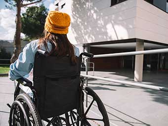 Frau im Rollstuhl vor einem Gebäude 