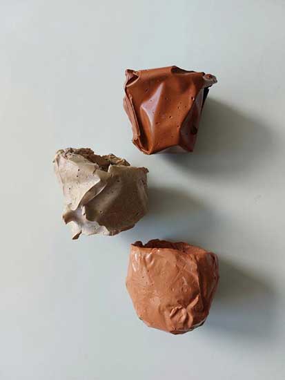 Drei Stücke Geopolymer mit glänzender Textur in unterschiedlichen Farben – Rotbraun, Hellbraun und Grau