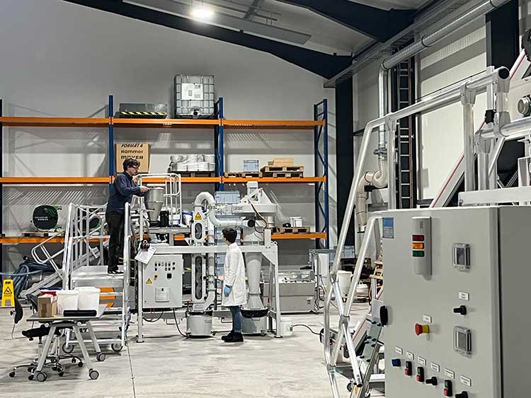 Zwei Männer bei der Arbeit am Zick-Zack-Sichter, einer Apparatur für die mechanische Zerkleinerung und Sortierung von recycelten Baumaterialien 