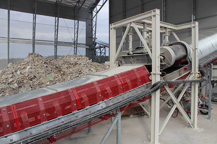Blick in eine Gips-Recyclinganlage: Das Foto zeigt ein Förderband mit Recyclingmaterial darauf 