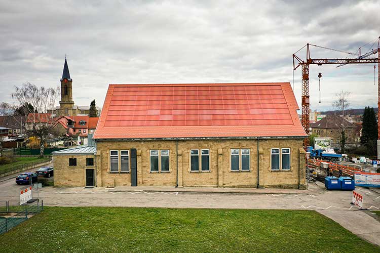 Historisches Gebäude in Eppingen mit einer roten, ins Dach integrierten Photovoltaik-Anlage. 