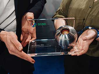 Das Bild zeigt die Hände von zwei Personen, die die Preisstatuette des Deutschen Nachhaltigkeitspreises Architektur halten. 
