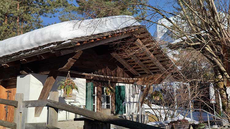 Holzhaus mit traditionellen Holzschindeln und schneebedecktem Dach 
