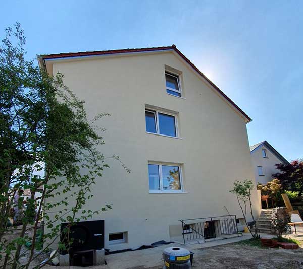 Das Bild zeigt das fertig sanierte Haus – unten links sieht man die Wärmepumpe.
