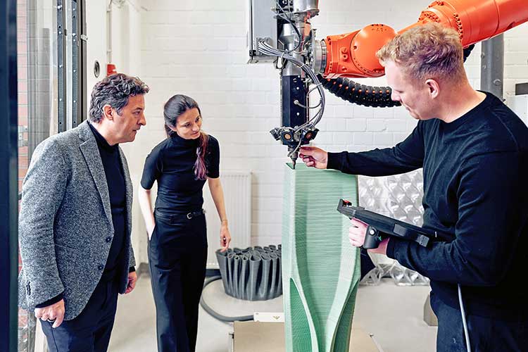 Das Bild zeigt Prof. Ulrich Blum (links), Moritz Wesseler (rechts) und Desislava Paneva (Mitte) am 3-D-Druckroboter des Fachbereichs Architektur der FH Münster. 