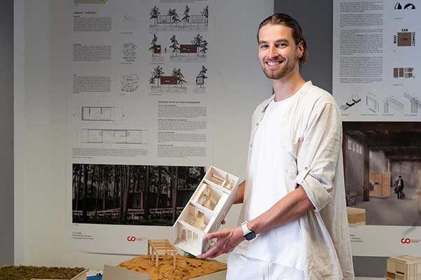 Das Bild zeigt den Studenten Jonas Reissing mit dem Modell seines Vorschlags für temporäre Wohnangebote für obdachlose Menschen
