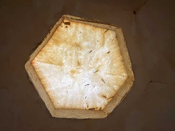 Foto: Braune Wand mit leicht ungleichmäßigem Farbverlauf. In der Mitte ist ein sechseckiger lichtdurchlässiger Bereich, der aber nicht transparent ist. Die Oberfläche wirkt texturiert und leicht rau.