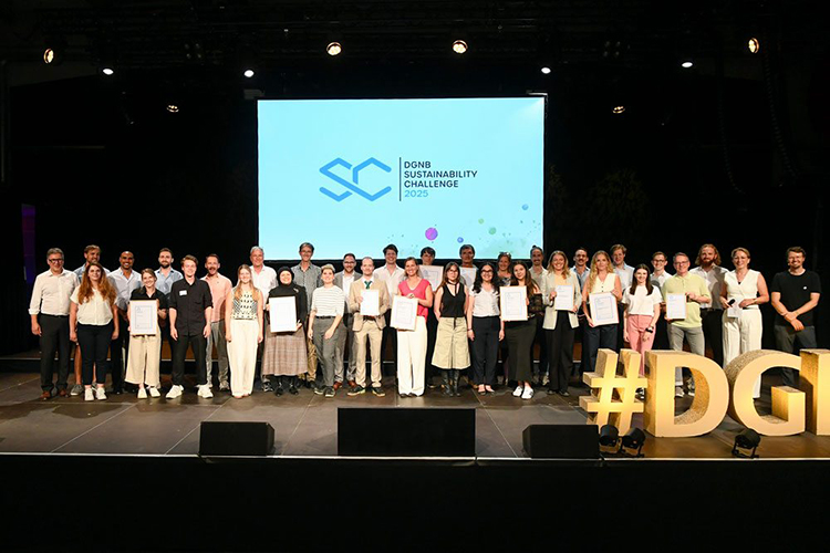 Gruppenfoto von mehreren Personen auf einer Bühne vor einer Leinwand mit dem Logo und Schriftzug „DGNB Sustainability Challenge 2025“. Die Personen stehen nebeneinander und halten Urkunden in den Händen. Rechts im Vordergrund steht eine leuchtende gelbe