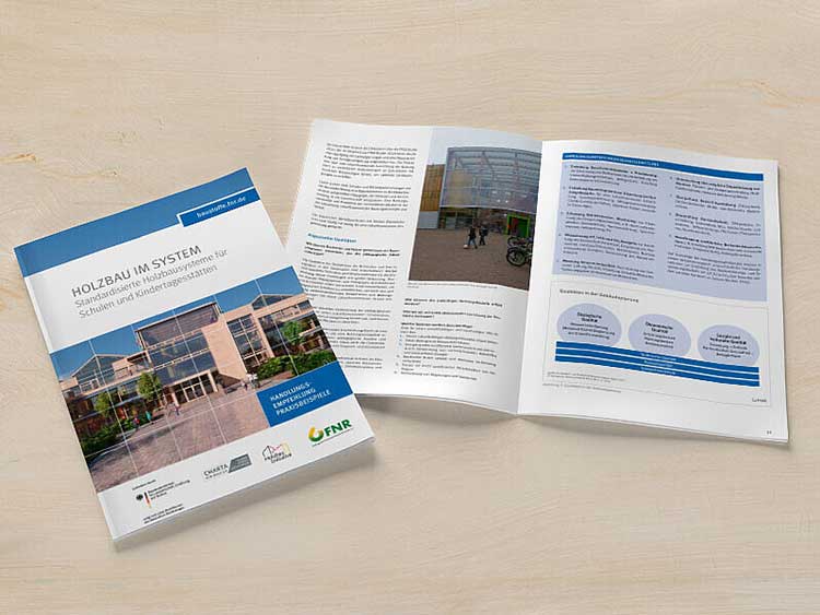Auf einem hellen Untergrund liegen zwei Exemplare der Broschüre »Holzbau im System«. Links ist das Cover zu sehen, das Exemplar rechts daneben ist aufgeklappt. 