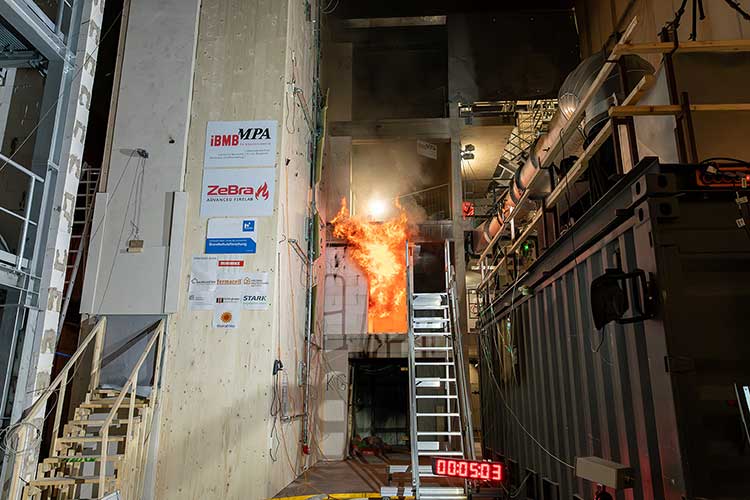 Versuchsaufbau zur Brandschutzprüfung. Ein intensives Feuer lodert in einem Testbereich. 